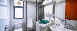 Un bagno con un WC, una cabina doccia in vetro, un lavandino e uno specchio.