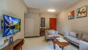 Una sala de estar con una televisión de pantalla plana, un sofá, una mesa de centro y obras de arte en las paredes.