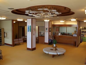A hotel lobby with a reception desk, seating area, and a unique circular seating arrangement. - Kutsuroginoyado Manseiro (Nachikatsuura)
