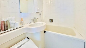 Un baño con lavamanos blanco, un espejo, inodoro y bañera.