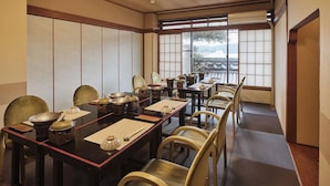 Un comedor tradicional japonés con esteras de tatami, mesas bajas y sillas de madera.