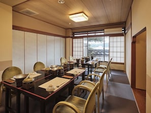 A traditional Japanese-style dining room with tatami mats, low tables, and wooden chairs. - Kutsuroginoyado Manseiro (Nachikatsuura)