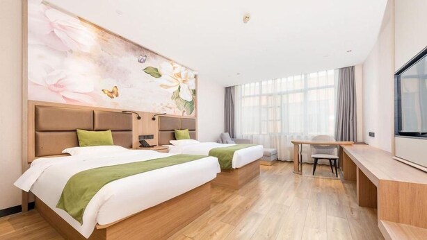 Ett hotellrum med två sängar, ett skrivbord, en stol och ett stort fönster.