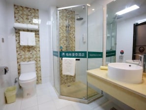 Ein Badezimmer mit Duschkabine, Toilette, Waschbecken und Spiegel.