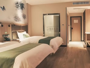 Ein Hotelzimmer mit zwei Betten, einem Nachttisch mit Telefon, einer Wandleuchte und einer Tür mit einem Schild.