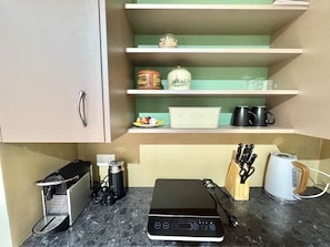 Et køkken med kaffemaskine, brødrister og et knivdisplay på disken.