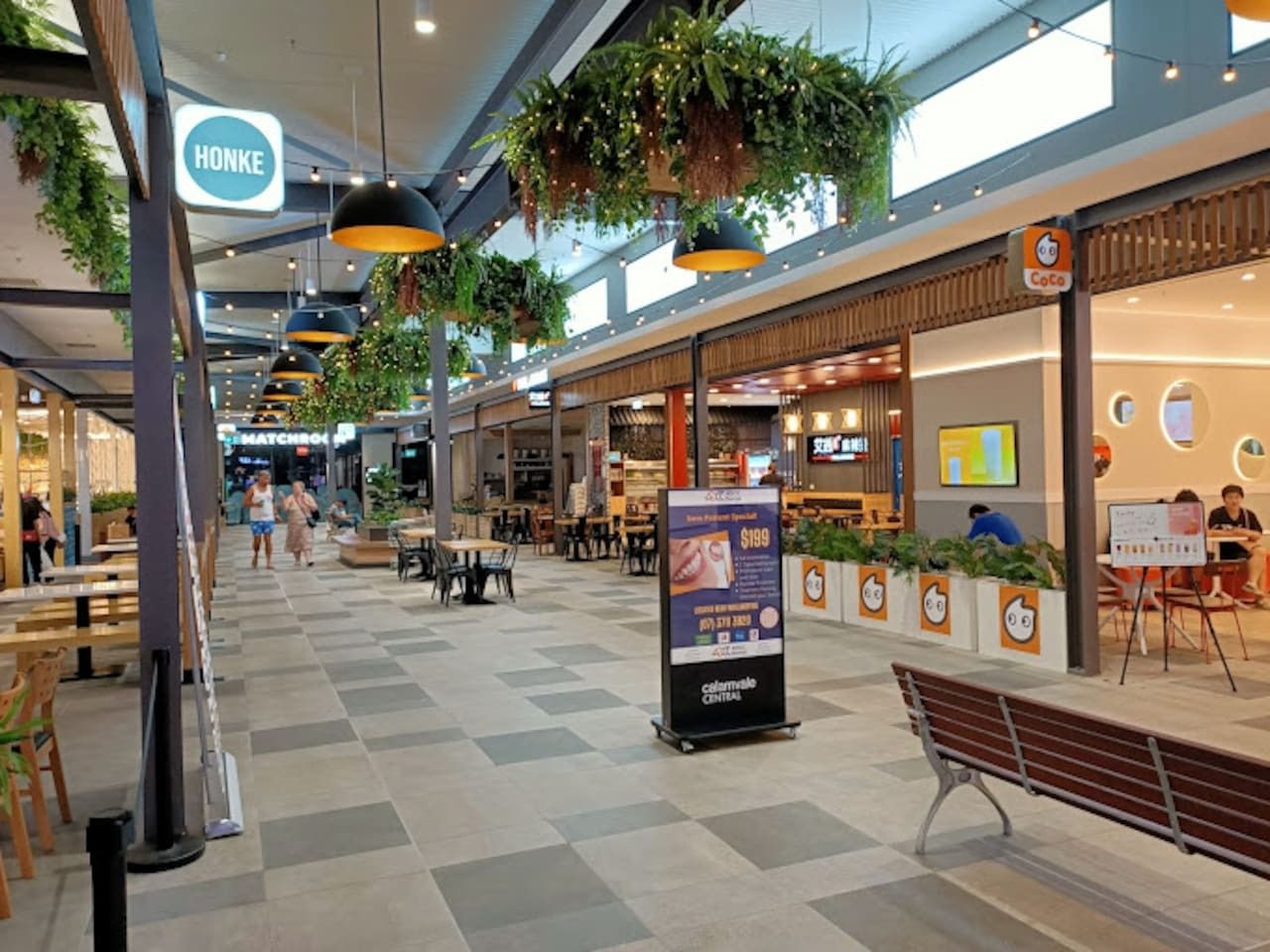 A spacious indoor area with a central walkway, benches, and tables.