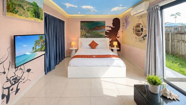 Een slaapkamer met een bed, een televisie en een schilderij van een strand.