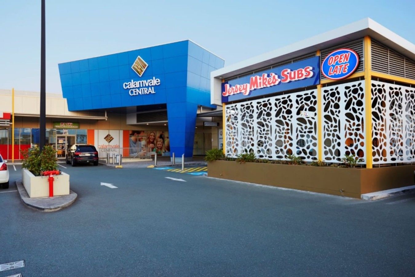 Un immeuble commercial à la façade bleue, sur lequel on peut voir une enseigne indiquant la présence d’un restaurant Jersey Mike’s Subs.