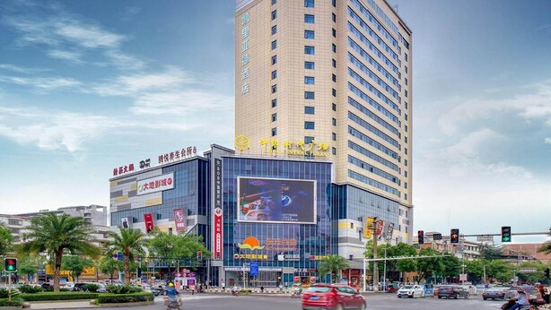 Un hôtel à plusieurs étages, doté d’une enseigne bien visible indiquant « Central Plaza » et d’un grand panneau publicitaire numérique.