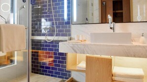 Une salle de bain moderne avec une douche à parois de verre, un lavabo blanc et un meuble-lavabo en bois.