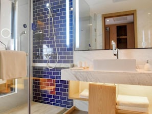 Un baño moderno con cabina de ducha de vidrio, lavamanos blanco y tocador de madera.