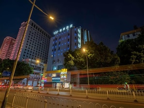 Un hotel a più piani con insegne illuminate, immerso nell'ambiente urbano e affacciato su una strada trafficata.