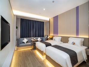 Habitación de hotel con dos camas, un sofá, un televisor y un escritorio con lámpara.