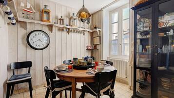 Un coin repas comprenant une table en bois, des chaises, une horloge et un buffet aux portes vitrées.