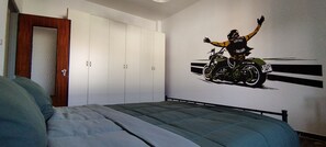 Ein Schlafzimmer mit einem Bett, einem Kleiderschrank und Wandbild eines Motorradfahrers.