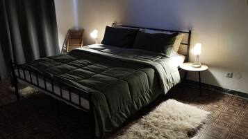 Un letto con una trapunta verde scuro, due lampade ai comodini e un tappeto decorato.
