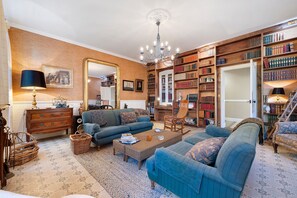 A spacious living room with a large bookshelf, a chandelier, and a comfortable seating area. - Villa Serpentine Guest Room – Parental Suite (Les Sables-d'Olonne)