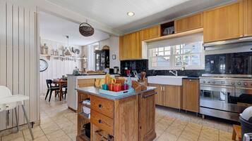 A kitchen with wooden cabinets, a central island, a stove, and a dining area with chairs.