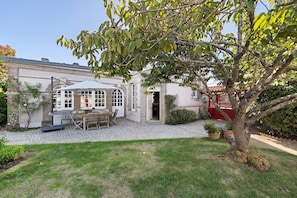 A courtyard with a patio table and chairs, a covered seating area, and a red gate. - Villa Serpentine Guest Room – Parental Suite (Les Sables-d'Olonne)