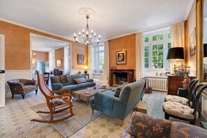 A spacious living room with a fireplace, comfortable seating, and large windows.