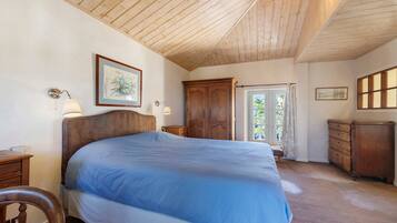 Un dormitorio con una cama grande, un armario de madera y una puerta que da a un balcón.