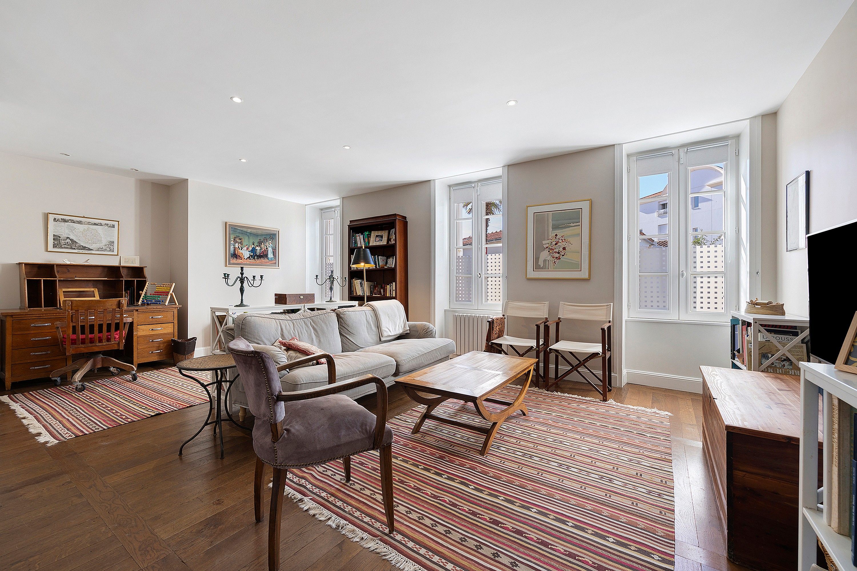 A spacious living room with a sofa, chairs, a coffee table, and a bookshelf.