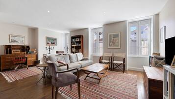 A spacious living room with a sofa, chairs, a coffee table, and a bookshelf.
