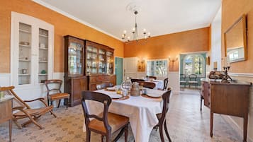Comedor con una gran mesa dispuesta para una comida, rodeada de sillas de madera.