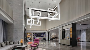 Um hall amplo com design moderno, com área de estar com sofá e poltronas, um tapete estampado e um balcão de recepção.