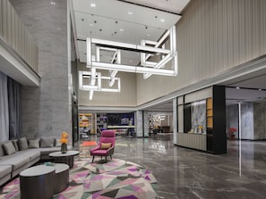 A spacious lobby with a modern design, featuring a seating area with a sofa and armchairs, a patterned rug, and a reception desk. - Hampton Inn Lianyungang (Lianyungang)