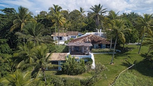A house surrounded by lush greenery and palm trees. - Hotel Fazenda Cala and Divino (Porto Seguro)