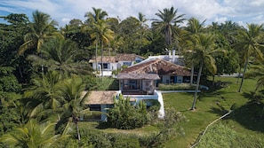 A house surrounded by lush greenery and palm trees. - Hotel Fazenda Cala and Divino (Porto Seguro)