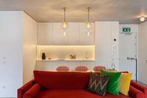 A modern living room with a red sofa, pendant lights, and a white cabinet with a shelf. - S Bento Residences Porto sao Bento (Porto)