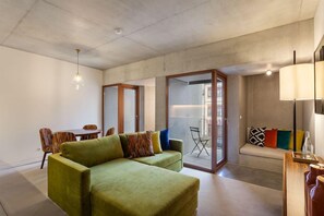 A modern living room with a green sofa, a dining table with chairs, and a sliding glass door leading to an outdoor area. - S Bento Residences Porto sao Bento (Porto)