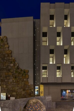 A modern building with a stone facade and multiple illuminated windows. - S Bento Residences Porto sao Bento (Porto)