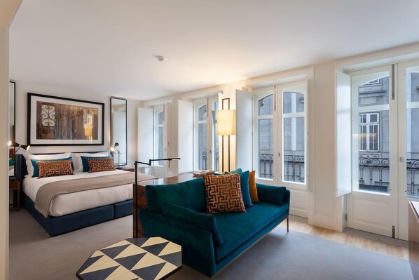 A modern hotel room with a bed, a sofa, a table, and large windows. - S Bento Residences Porto sao Bento (Porto)