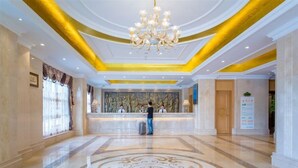 A hotel lobby with a reception desk, a chandelier, and a decorative floor pattern. - Vienna International Hotel (Enshi)