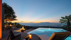 Una piscina infinità amb vista a un paisatge urbà al capvespre.