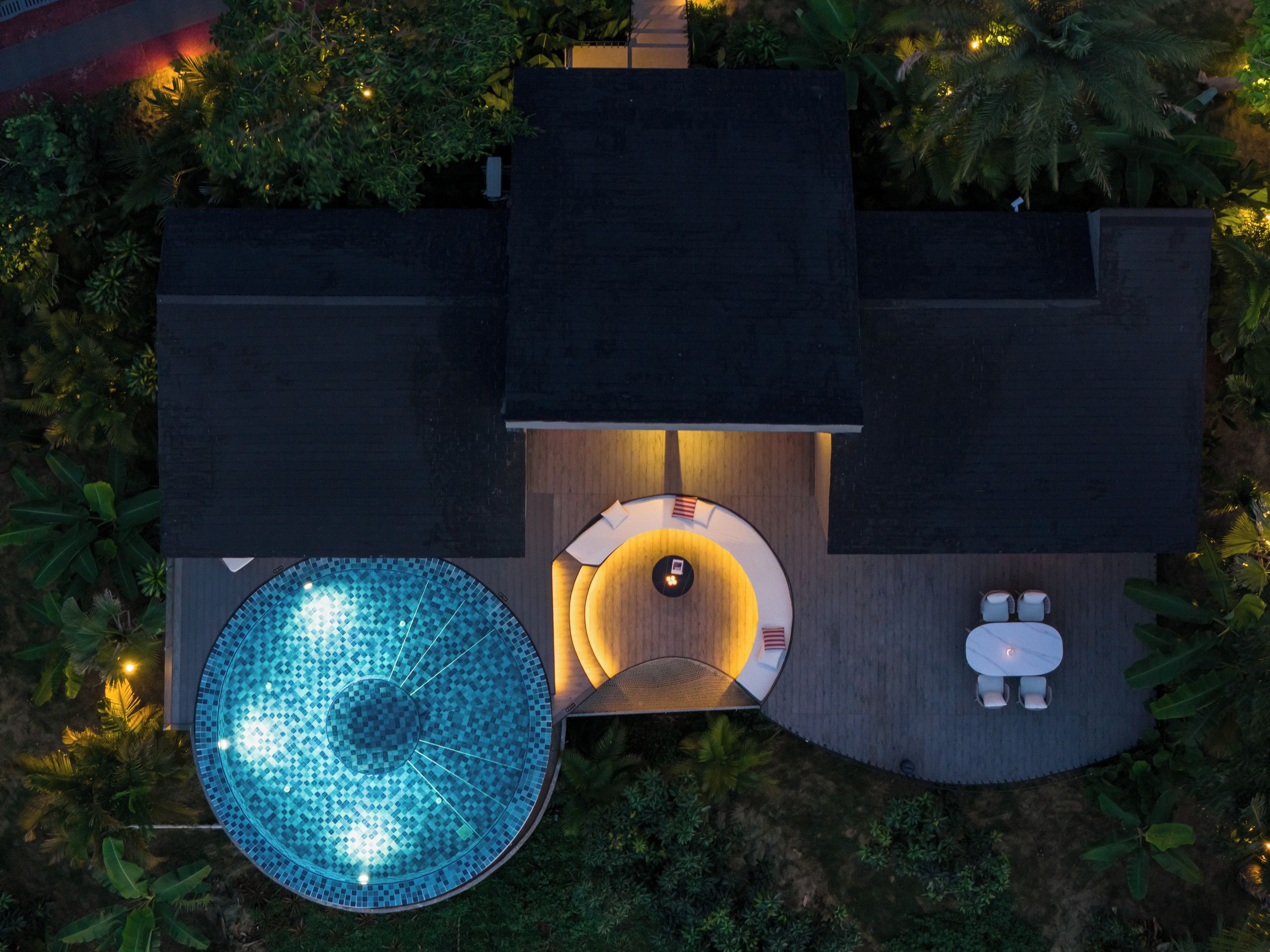 A top-down view of a modern outdoor area with a swimming pool, a sunken seating area, and a small table with chairs.