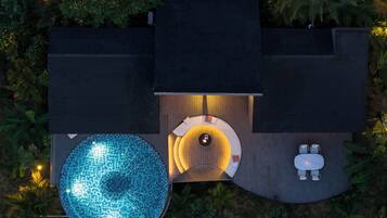 A top-down view of a modern outdoor area with a swimming pool, a sunken seating area, and a small table with chairs.