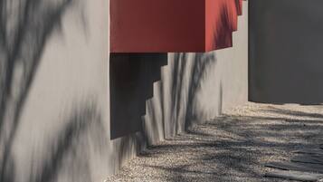 A person ascending a red staircase with a grey wall in the background.