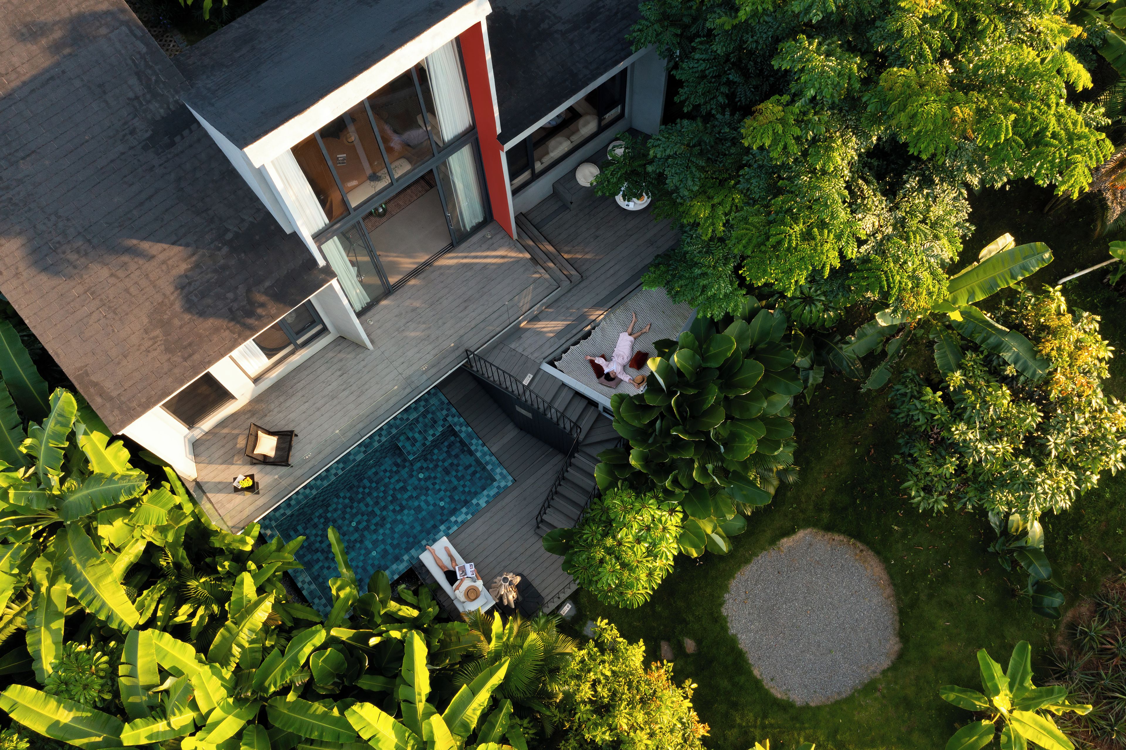 Ein modernes Haus mit Swimmingpool, Sitzgelegenheiten im Freien und üppiger Bepflanzung.