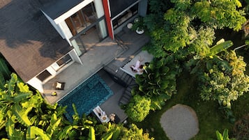 A modern house with a swimming pool, outdoor seating, and lush greenery.
