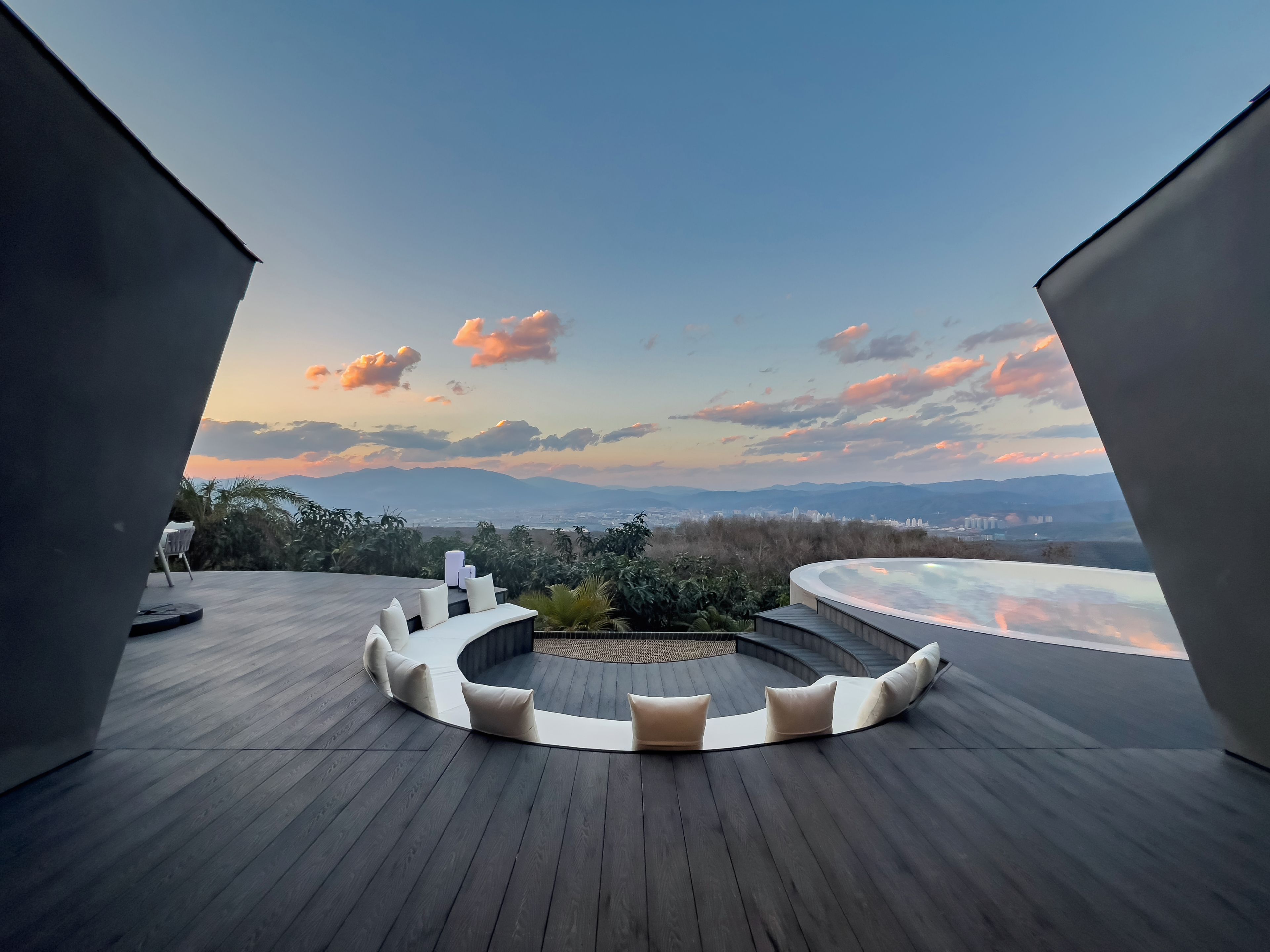A modern outdoor deck with a circular seating area and a panoramic view of the landscape.