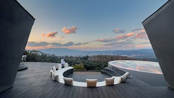 A modern outdoor deck with a circular seating area and a panoramic view of the landscape.