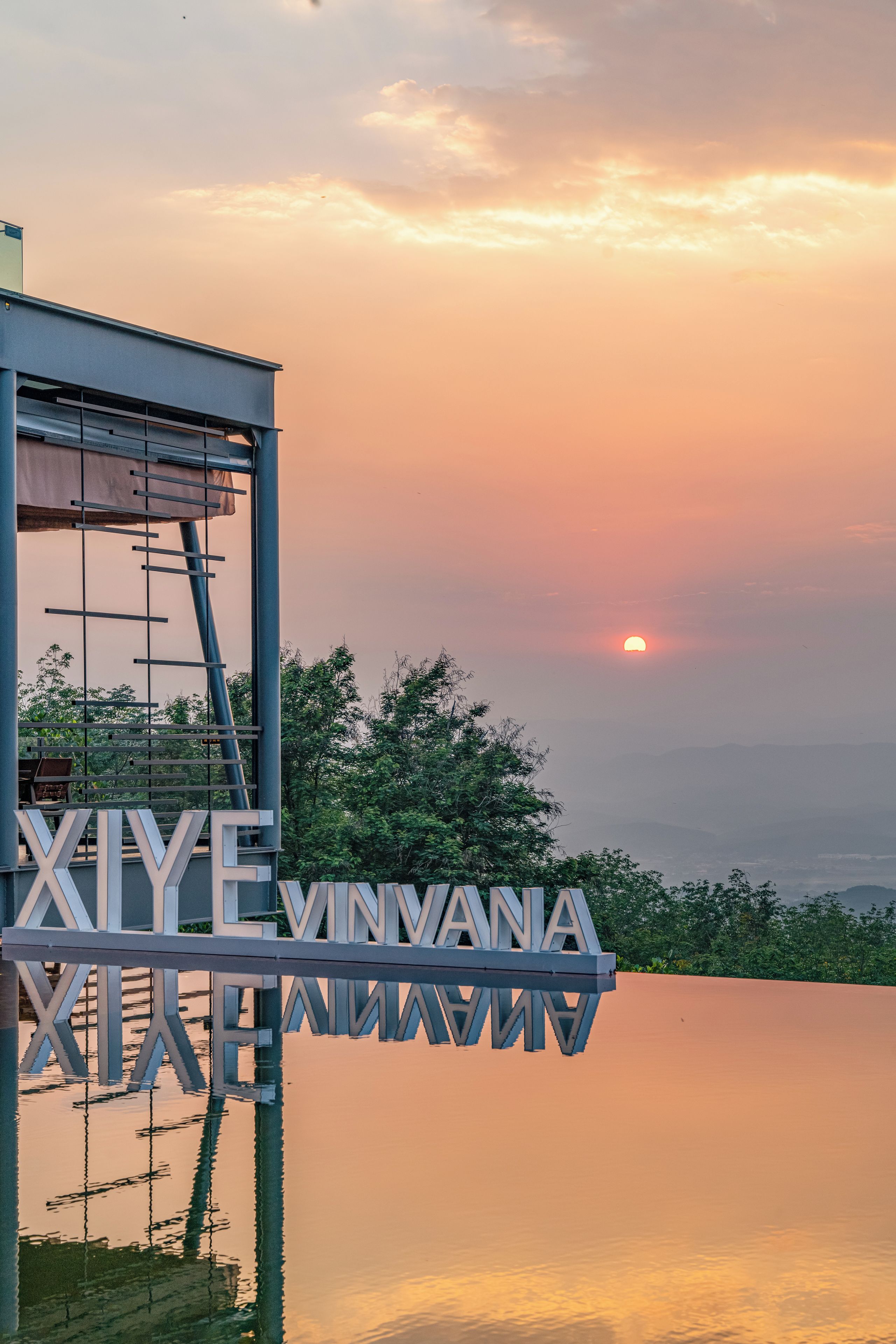 A modern building with a large sign reading 'XIYE VINYANA' reflecting in the water.