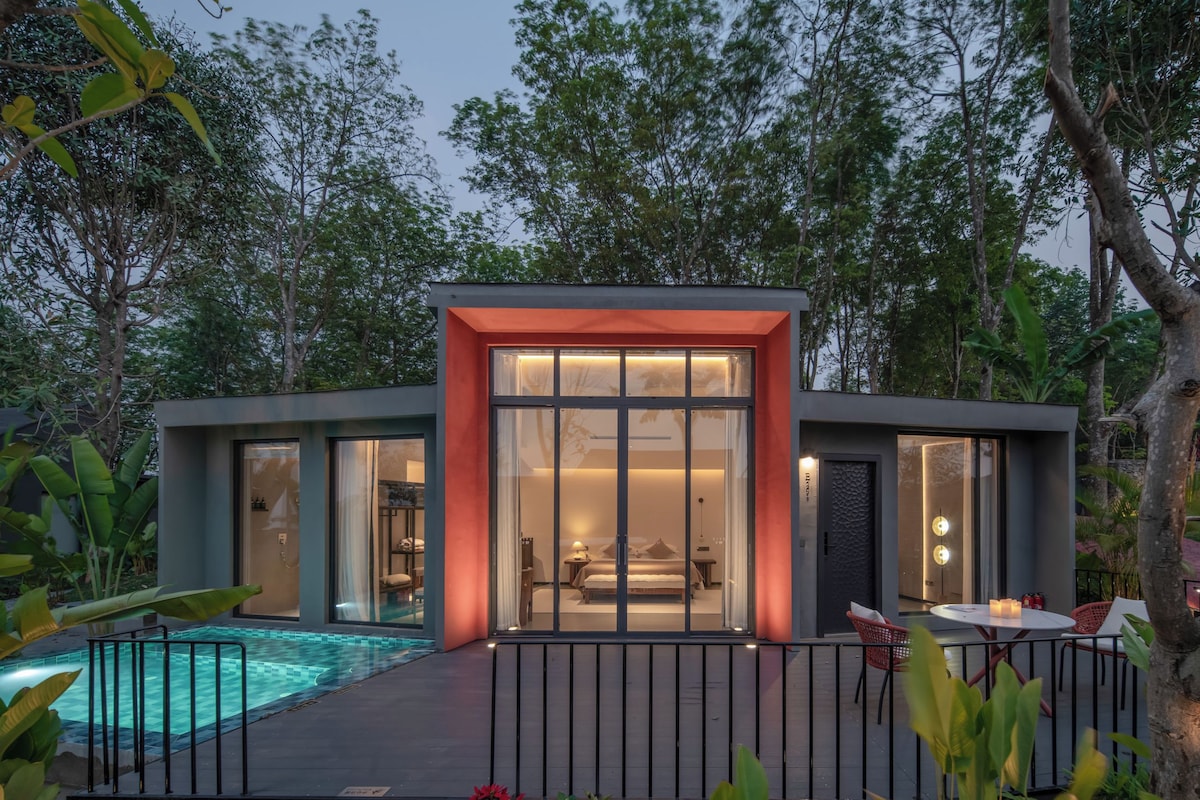Een modern huis met een glazen gevel, een zwembad en een terras.