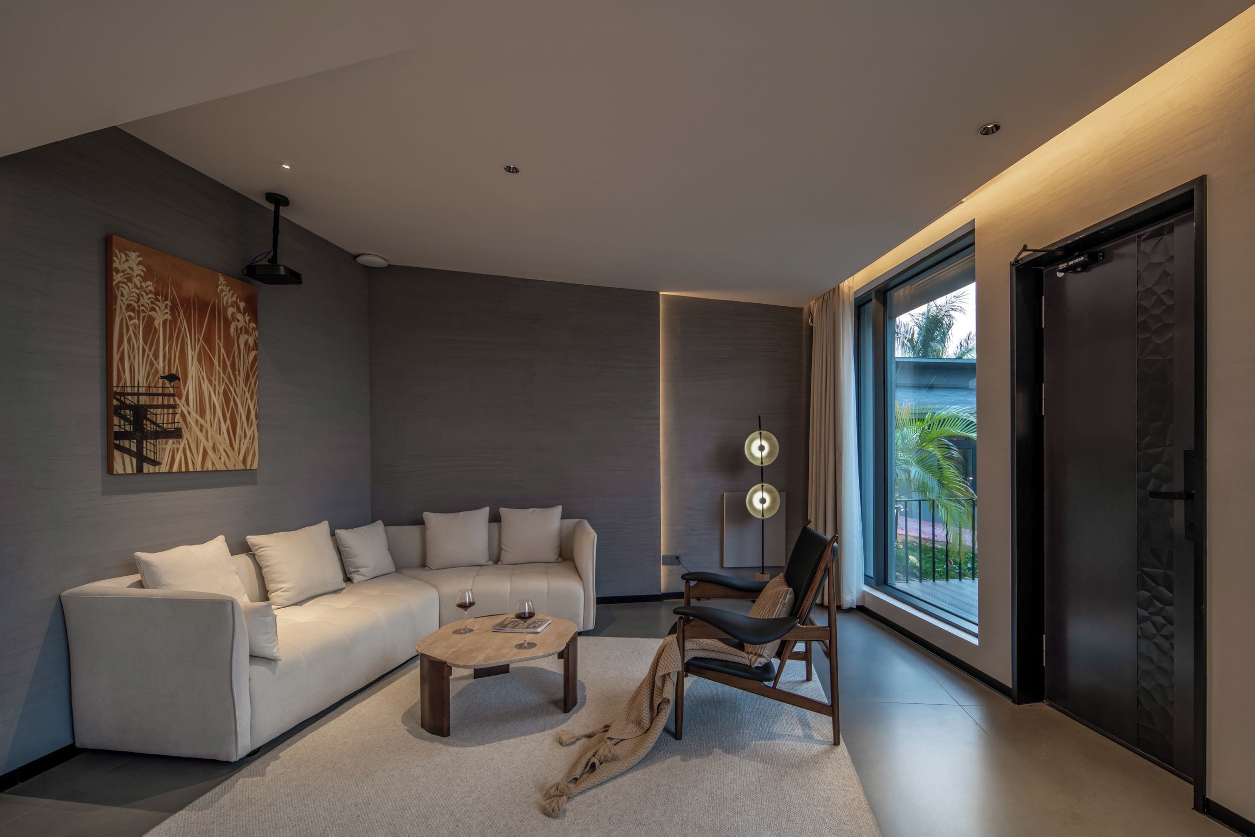 A modern living room with a sectional sofa, a coffee table, a chair, and a large window providing a view of the outdoors.
