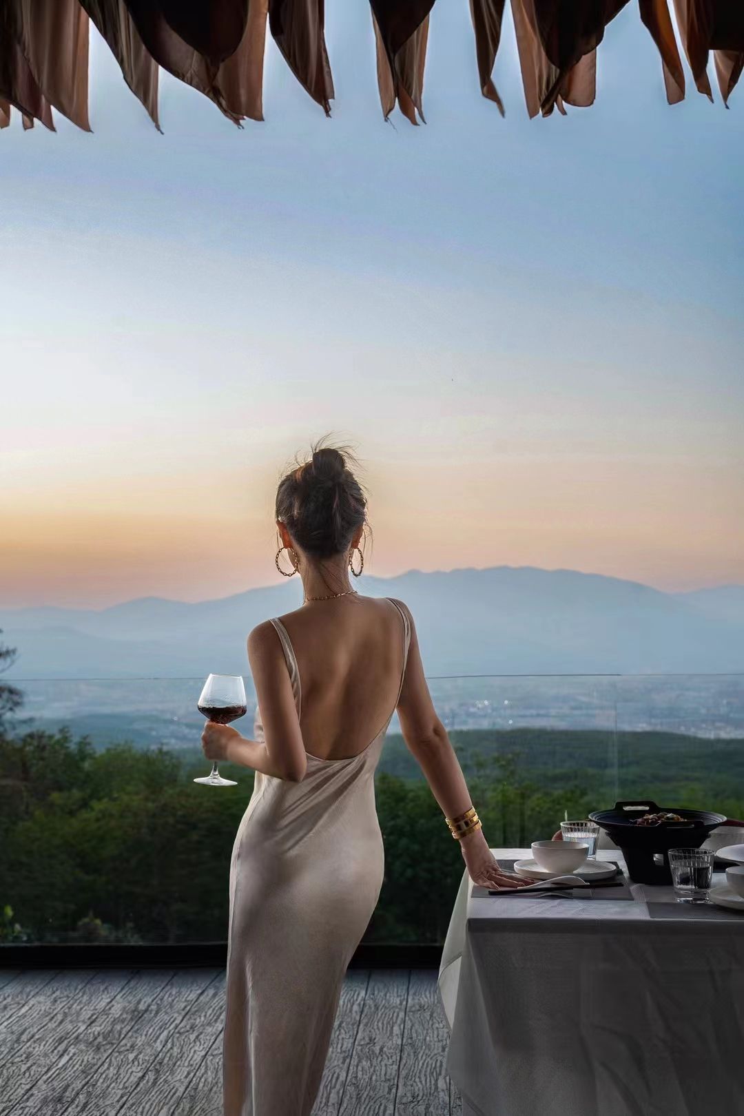 A person seated at a table with a view of a landscape.